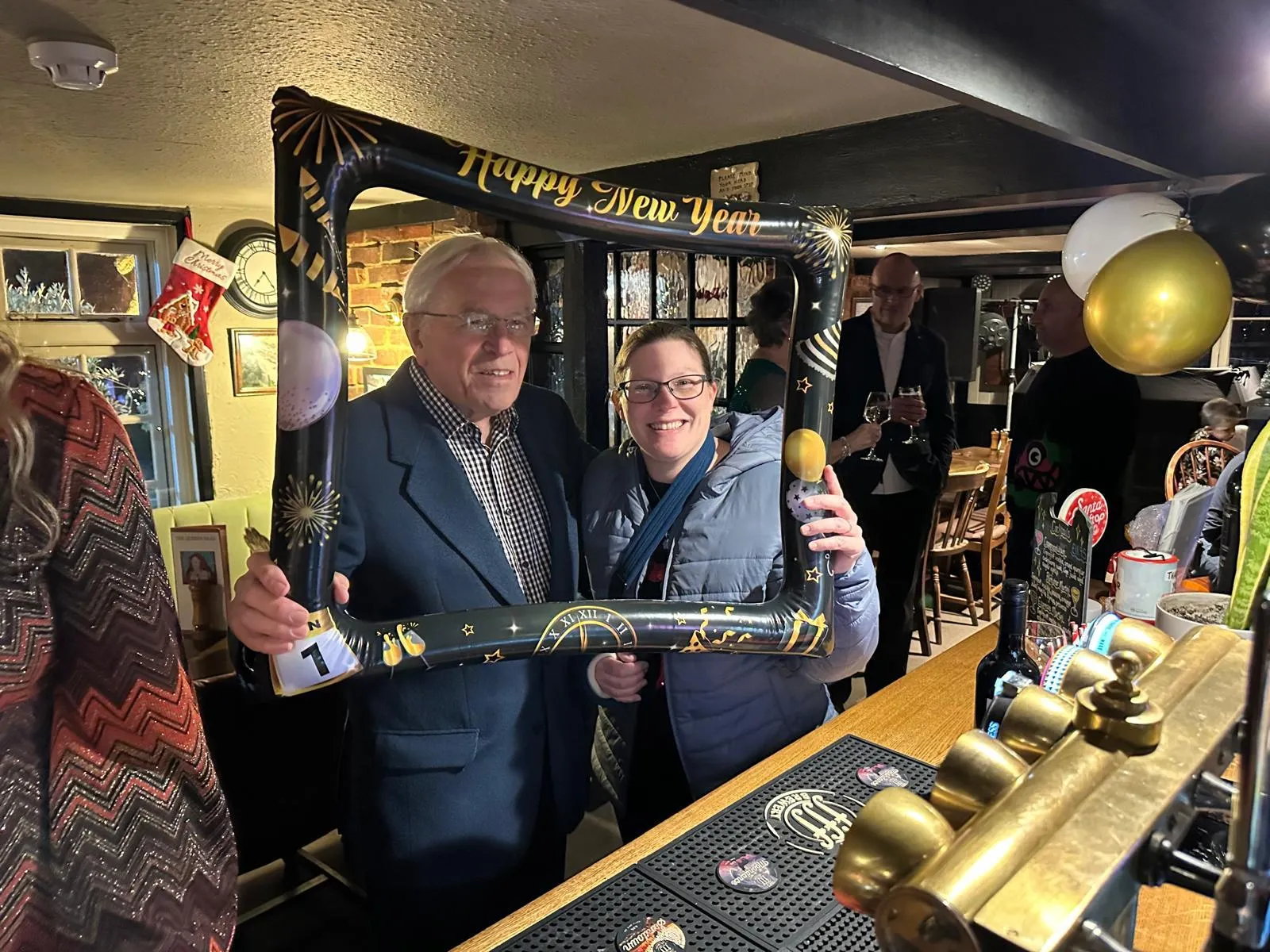 Guests raising a toast at the bar beside the hand pumps