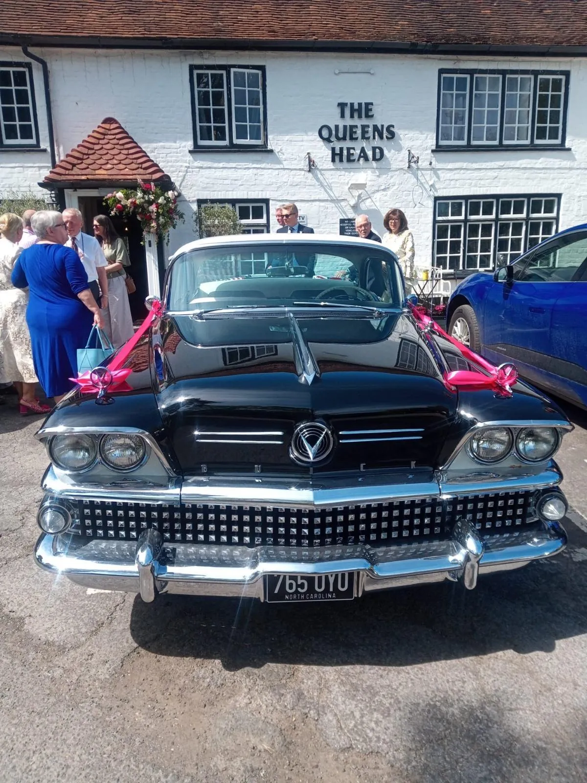 A ribboned vintage wedding car parked at the front door of the Queens Head